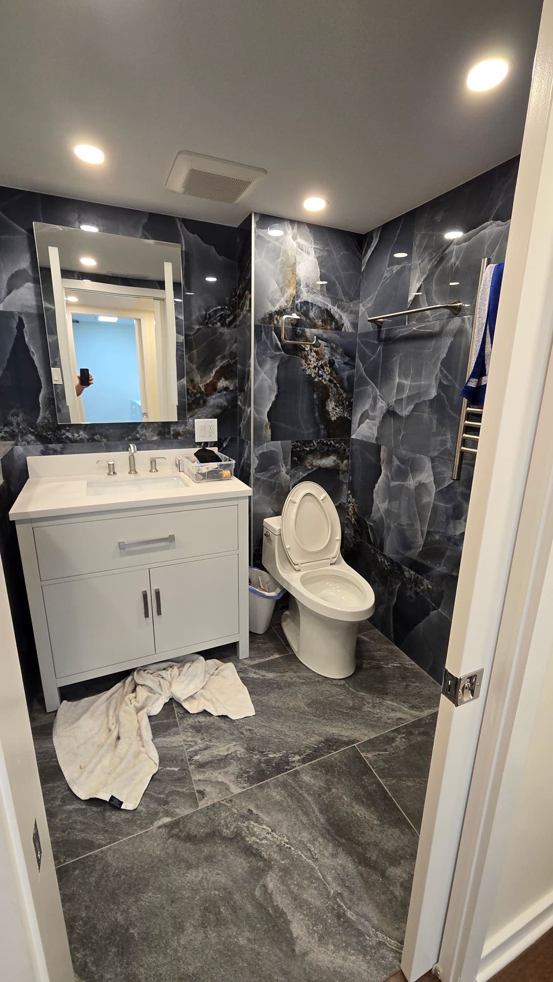 Dramatic black onyx look shower tile with gray vanity
