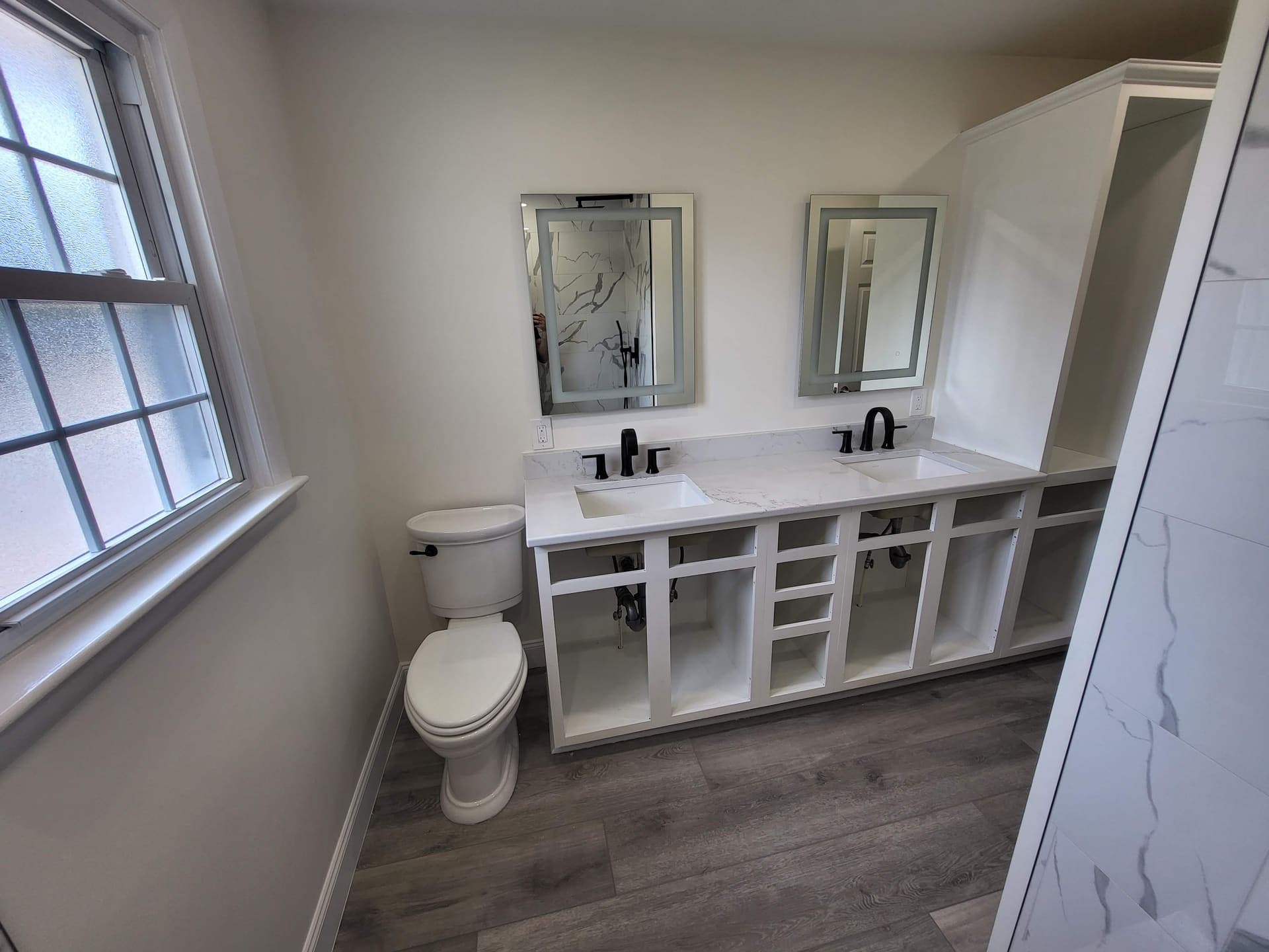 Double vanity bathroom with LED mirrors and black faucets