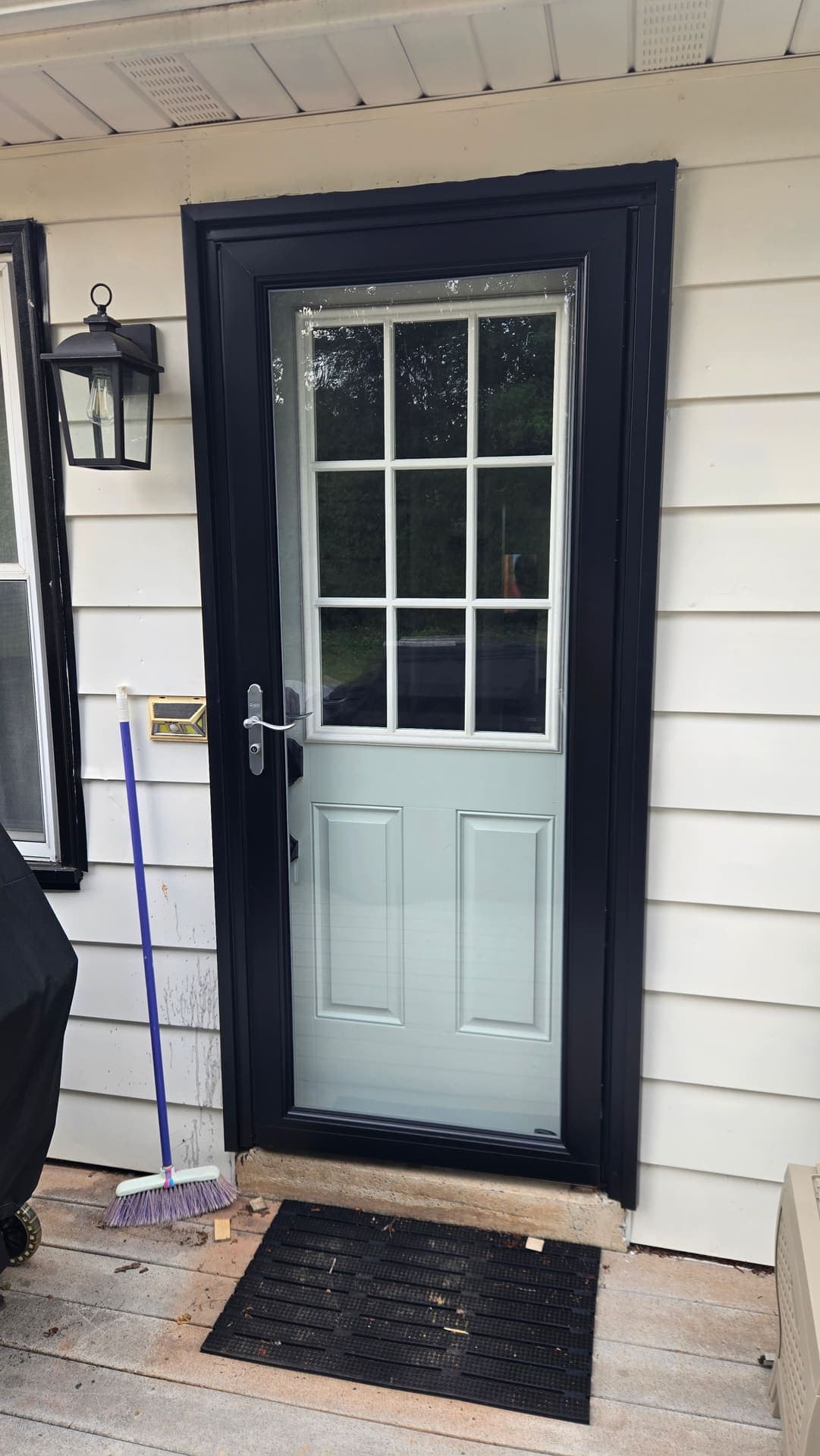 Black storm door on a board and batten siding porch