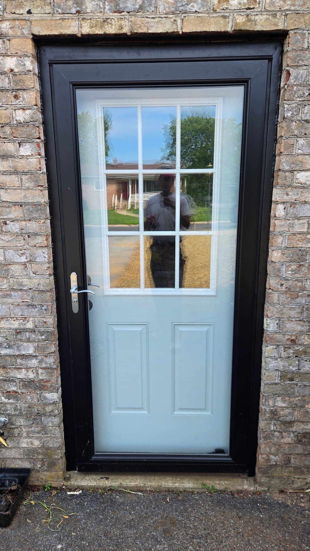 New black storm door with nine lite glass on brick