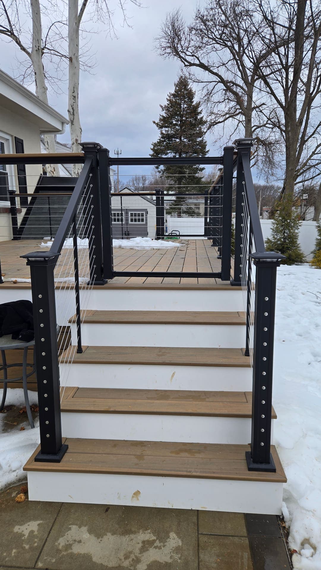 Close up of composite deck stairs with black cable railing