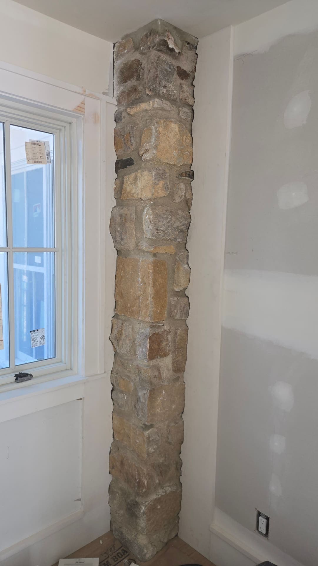 Freshly taped drywall around an exposed stone accent beam