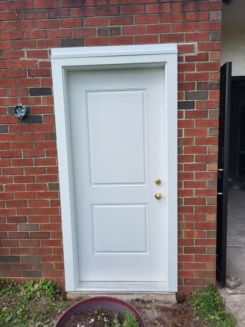 New white exterior entry door installed in a brick wall