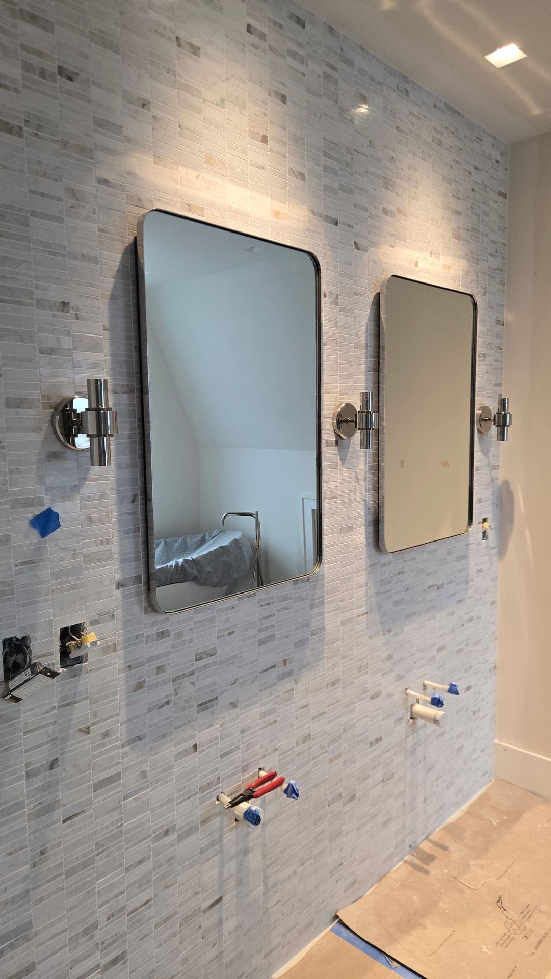 Marble mosaic vanity wall with sconces being installed