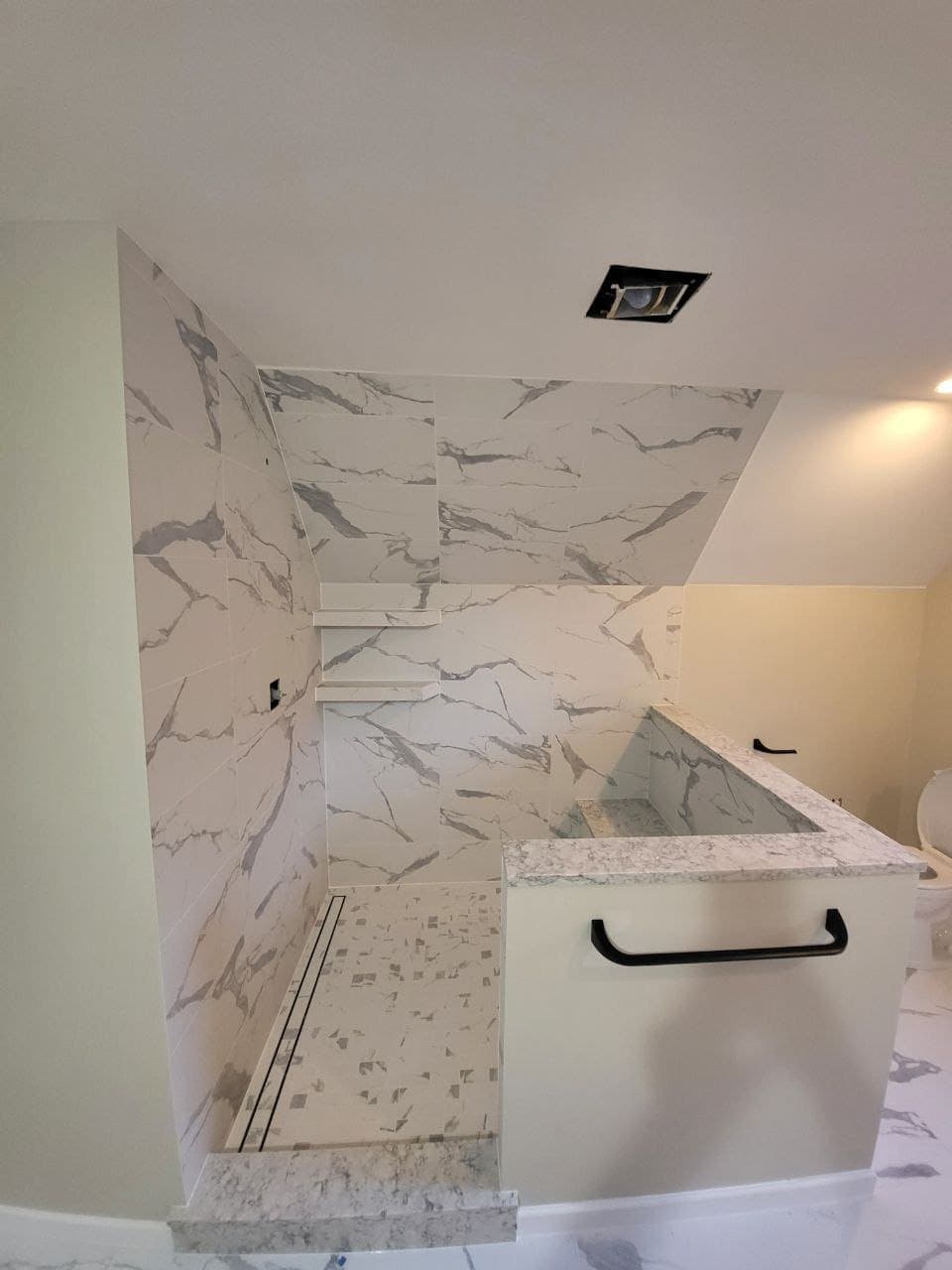 Marble tile shower with mosaic pan, quartz curb and linear drain