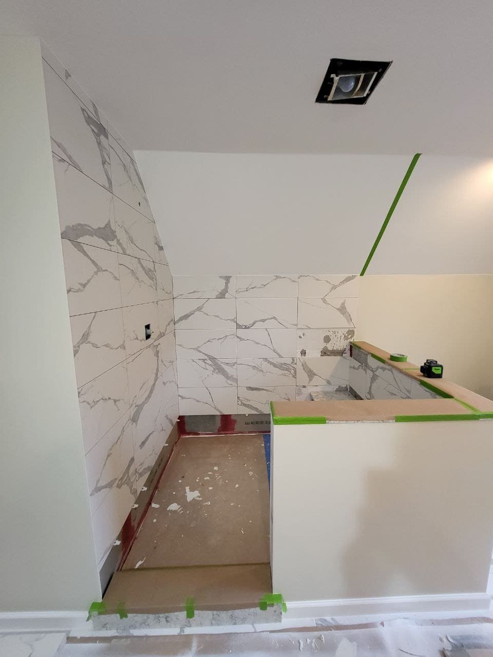 Marble look shower wall tile being installed