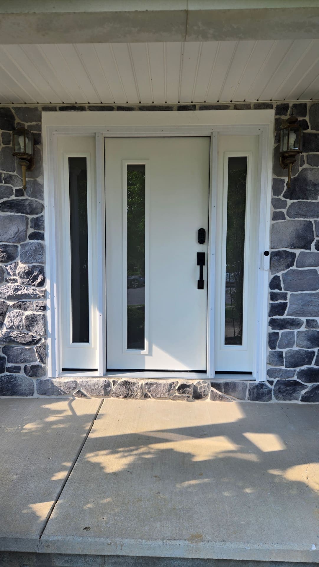 Modern front door with sidelites on a stone facade