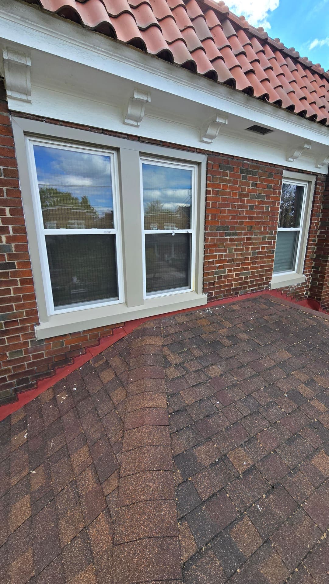 New replacement windows with tan trim on a brick bay