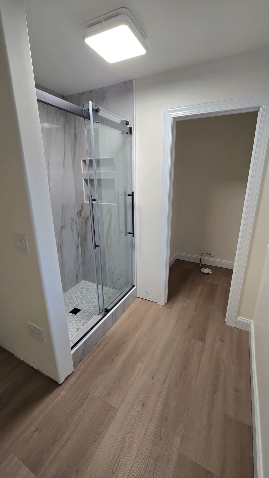 Walk-in shower with glass slider, marble look tile and niches